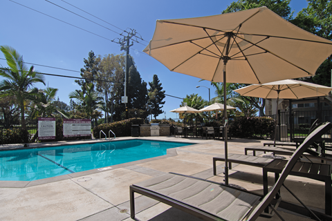 A pool area with a sun umbrella and a sign that says 